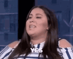 a woman in a blue and white striped shirt is making a funny face and saying yes .