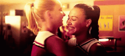 two cheerleaders are hugging each other in a room .