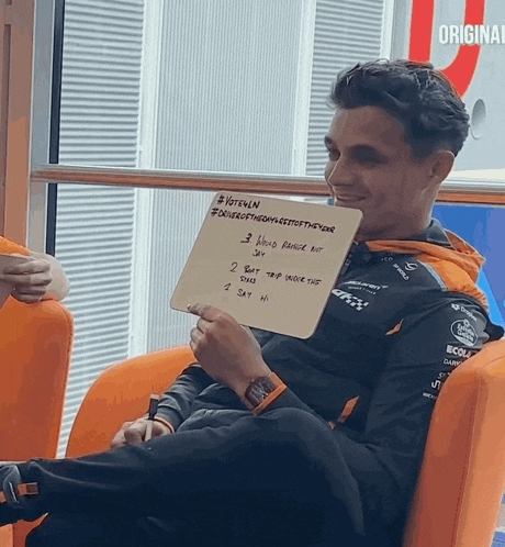a man sits in an orange chair holding a sign that says ' veteran ' on it