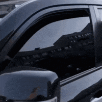 a black car with the door open and a reflection of a building in the window