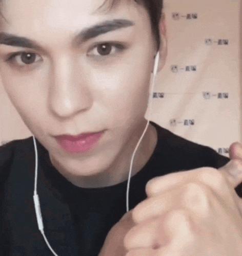 a close up of a person wearing headphones and making a heart shape with their hands