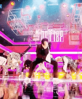 a group of people are dancing on a stage in front of a crowd of people .
