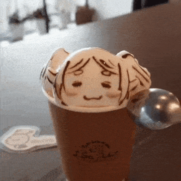 a cup of coffee with a face drawn on it and a spoon .