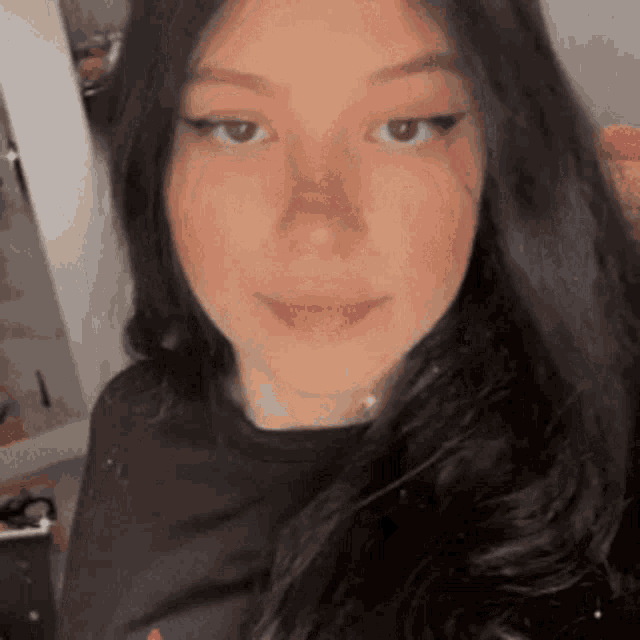 a close up of a woman 's face with long dark hair and a black shirt .