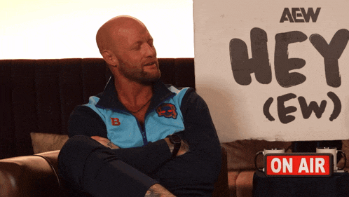 a man sitting in front of a sign that says hey ew