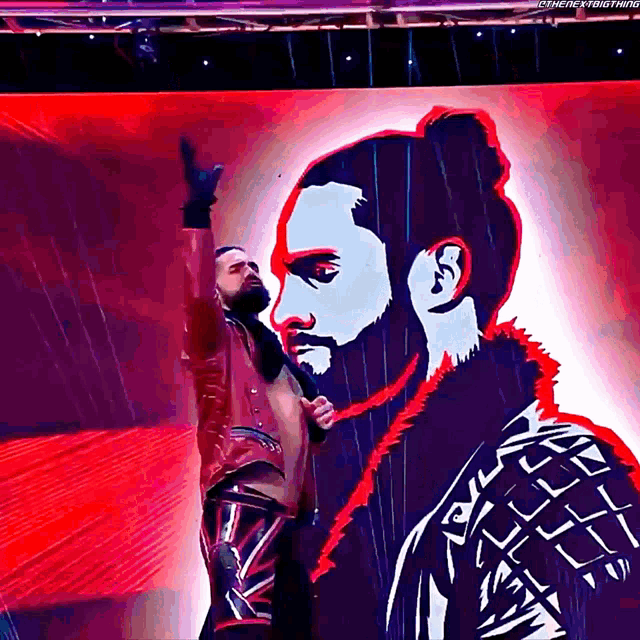 a man with a beard is standing in front of a large screen that says ' i 'm here everything ' on it