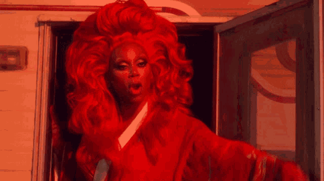 a woman in a red wig is standing in front of a door