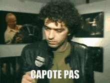 a man in a leather jacket is holding a microphone and says " capote pas "