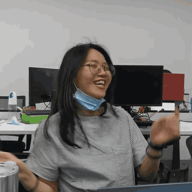 a woman wearing glasses and a mask is sitting in front of a dell computer