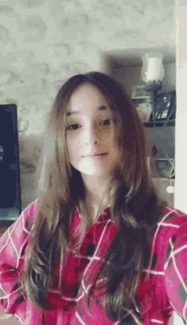 a young girl with long hair is wearing a pink plaid shirt