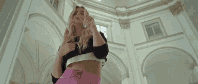 a woman in a black top and pink shorts is standing in a large room