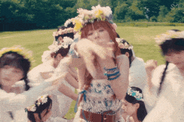 a woman wearing a flower crown is surrounded by other girls