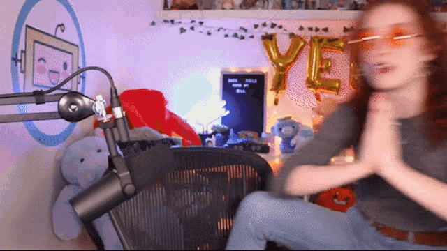 a woman sitting in front of a microphone with a balloon that says ye