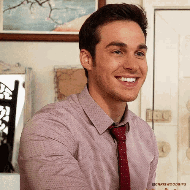 a man wearing a pink shirt and red tie is smiling for the camera
