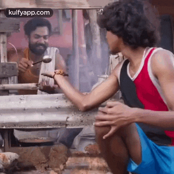 a man is holding a spoon in his hand while another man holds a spoon in his hand .