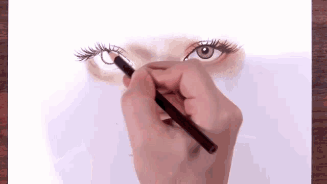 a person is drawing a woman 's eye with a pen on a piece of paper .