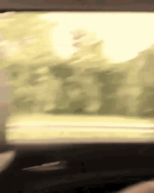 a blurry picture of a person driving a car with the sun shining through the window