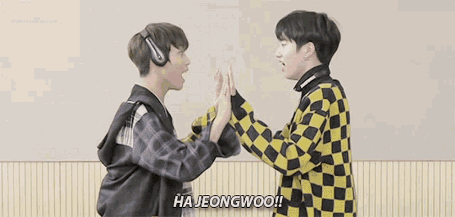 two young men are giving each other a high five .