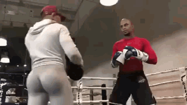 two men are standing in a boxing ring .