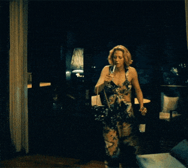 a woman in a floral dress is drinking from a bottle