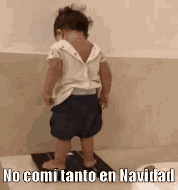 a little girl is standing on a scale with the words `` no comi tanto en navidad '' written on it .