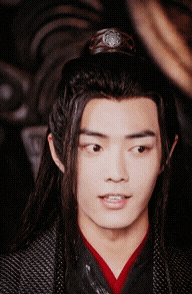a young man with long hair and a crown on his head looks at the camera
