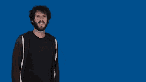 a man with a beard stands in front of a blue background with the word yo written in white