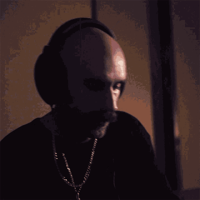 a man with a beard wearing headphones and a chain around his neck