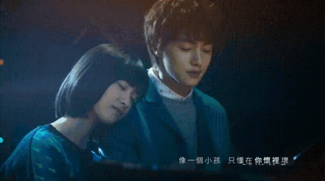 a man and a woman are sitting next to each other with chinese writing on the screen