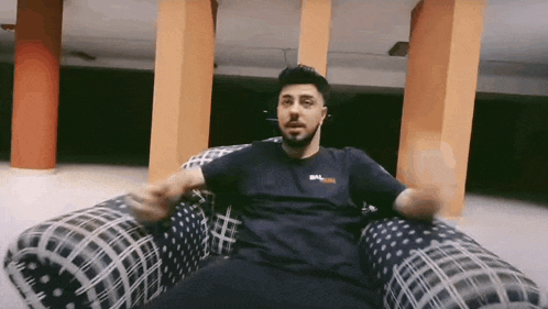 a man with a beard is sitting in an inflatable chair in a room .