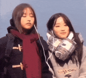 two young women wearing scarves and ear buds are standing next to each other