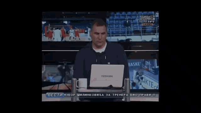 a man stands in front of a laptop that says toshiba on it