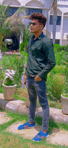 a young man wearing a green shirt and blue shoes is standing in front of a building