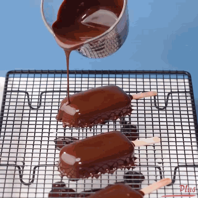 chocolate is being poured on ice cream bars on a wire rack