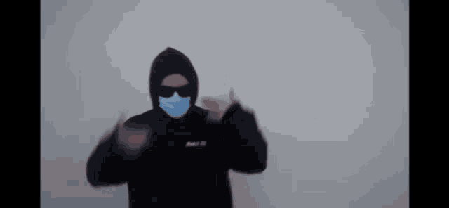 a man wearing a face mask and sunglasses is making a peace sign .