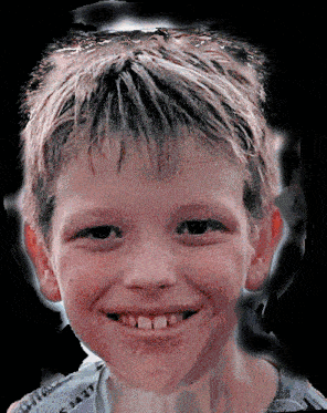 a close up of a young boy 's face with a black background and a smile