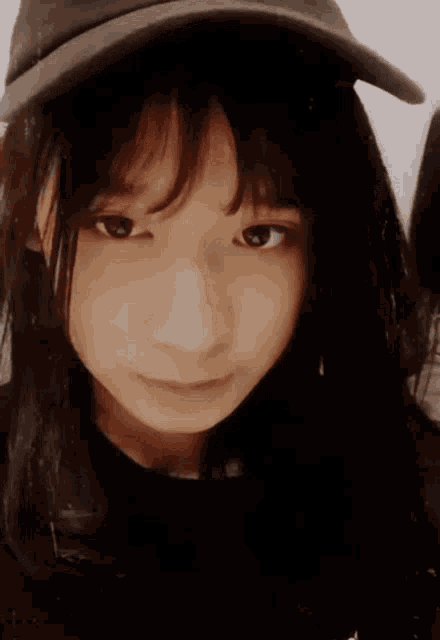 a young girl wearing a hat and a black shirt looks at the camera