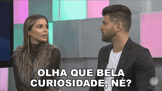 a man and a woman are sitting in front of a screen with the words olha que bela curiosidade