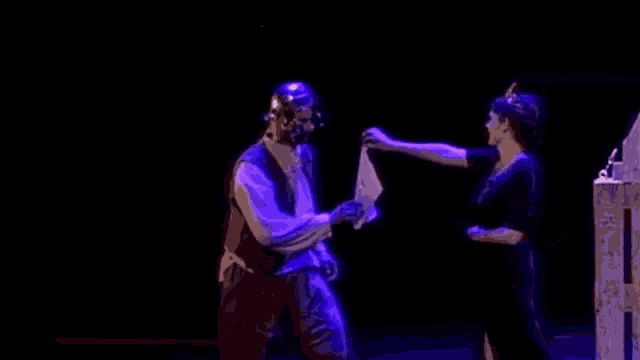 a man and a woman are standing on a stage in the dark .