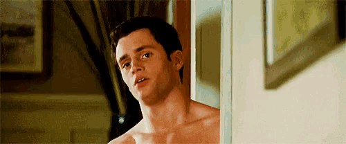 a shirtless man is standing in a doorway looking out .