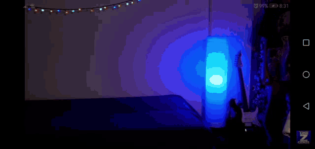 a bedroom with a blue lamp and a guitar on the floor .