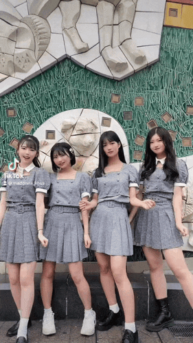 four girls are posing for a picture in front of a statue with tiktok written on the bottom