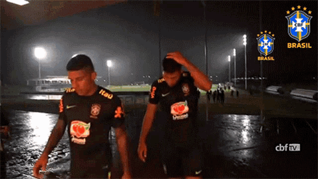 two soccer players are walking in the rain with logos for brasil on the bottom