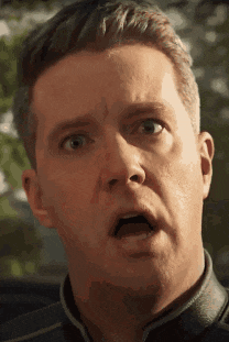 a close up of a man 's face with his mouth open and a surprised look on his face .