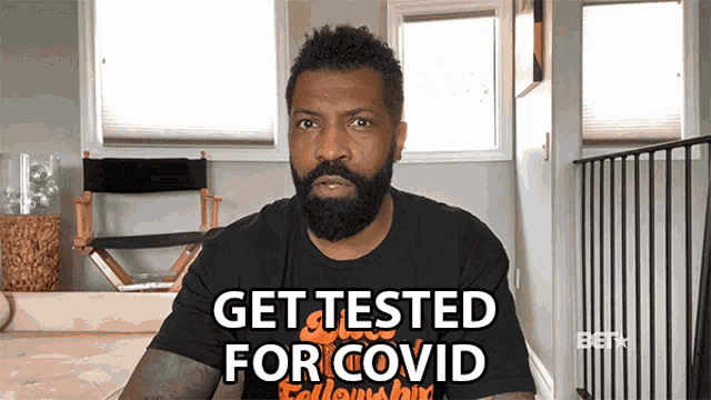a man with a beard wears a black shirt that says get tested for covid