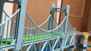 a toy bridge is sitting on top of a wooden table next to a window .
