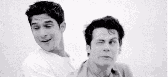 a black and white photo of two men standing next to each other and making funny faces .