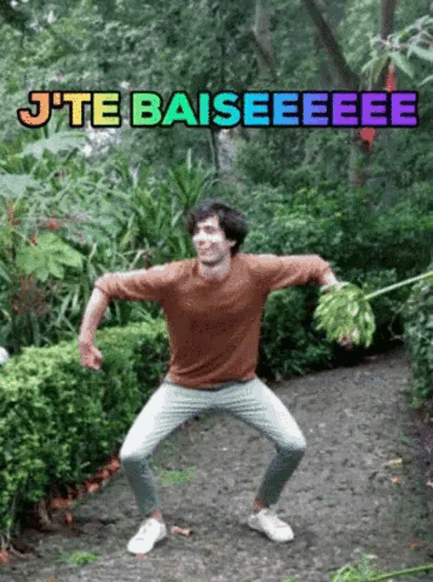 a man in a brown shirt is holding a bunch of leaves and says j'te baiseeee