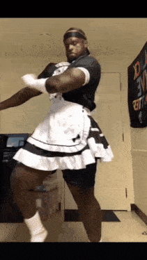 a man in a maid costume is dancing in front of a sign that says " i love u "