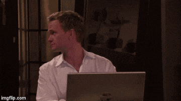 a man in a white shirt is sitting in front of a laptop computer and smiling .